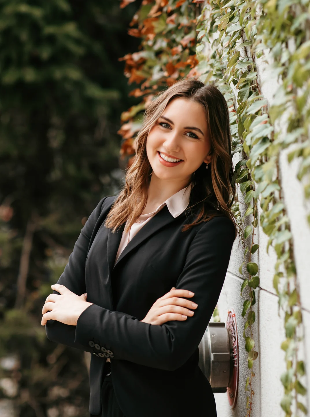 Anya Polanski in a dark blazer beside a leafy wall